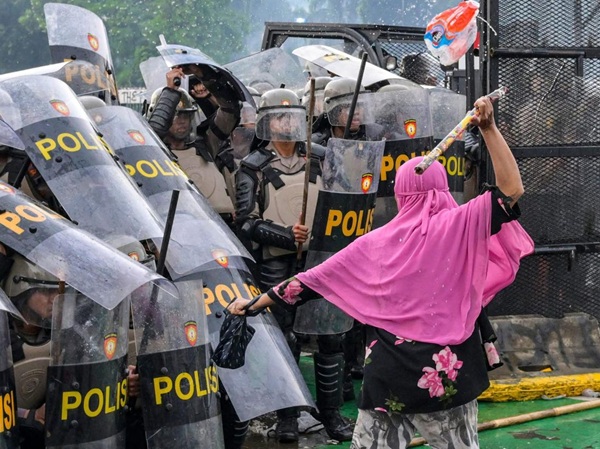 Young female protester confronting massed riot police