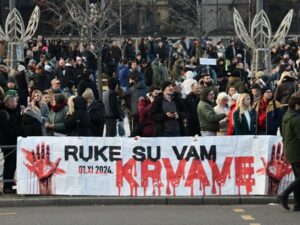 Banner at front of demonstration in Serbia reading "Your hands are dripping blood"